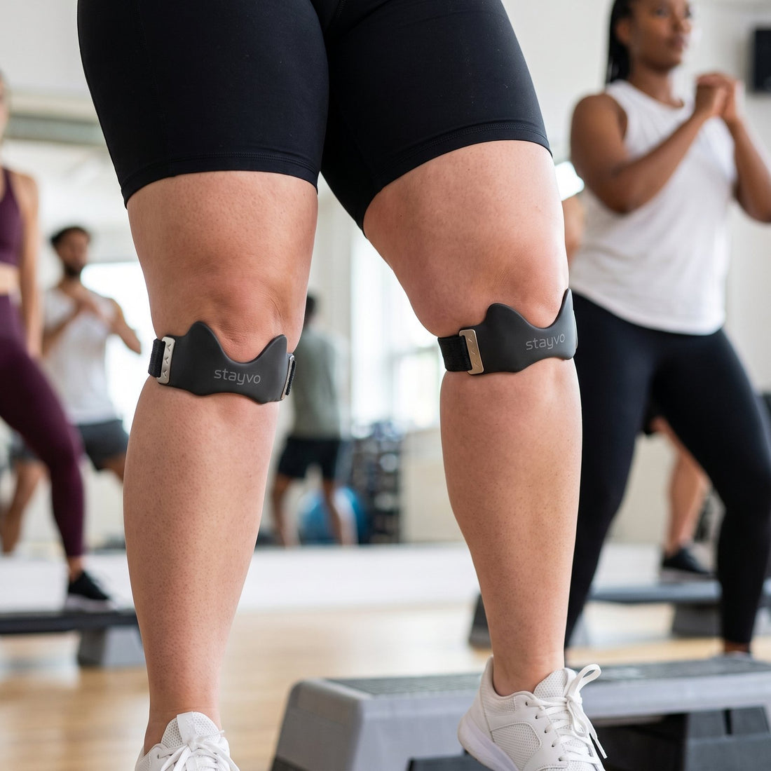 Legs on an aerobic step in a gym class, a Stayvo strap under each kneecap